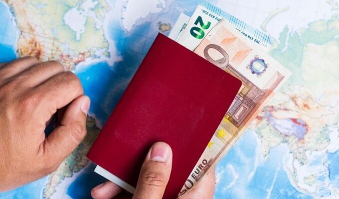 banknoty euro w paszporcie na tle mapy świata